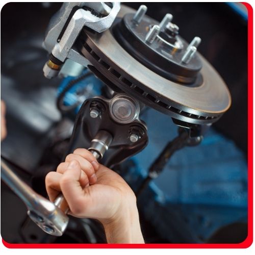 Mechanic using a ratchet to secure bolts on a brake rotor during a vehicle brake service.