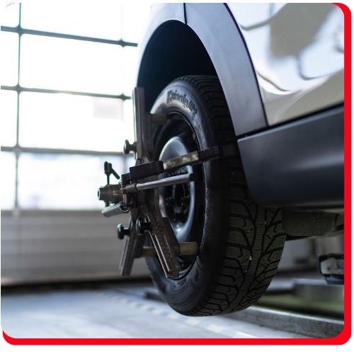 Close-up of a vehicle wheel with alignment tool attached during CV axle inspection.