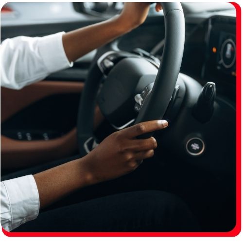 Driver holding steering wheel, potentially experiencing vibration from CV axle issues.