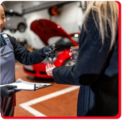 Customer receiving car keys from a mechanic after a completed oil change service.