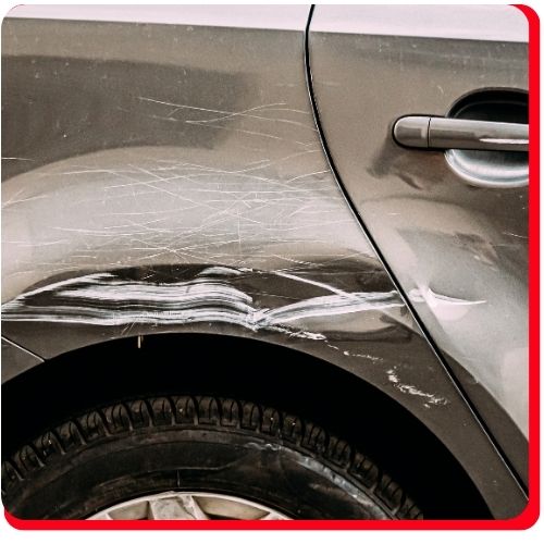 Multiple scratches and a dent on the rear door and fender of a dark-colored car.