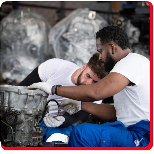 Two auto technicians inspecting a vehicle transmission during an overhaul service.