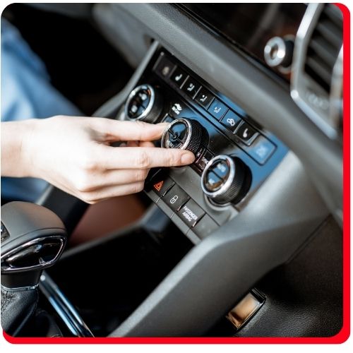 Hand adjusting car air conditioning dial on the dashboard climate control system.