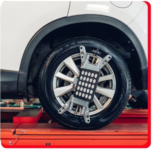 Close-up of a car tire with a digital wheel alignment sensor attached.
