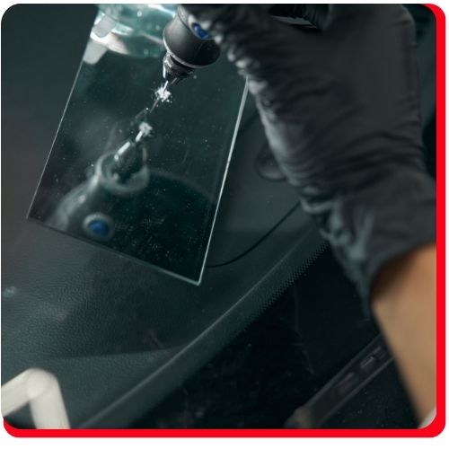 Technician using a precision tool to inject resin into a windshield chip for repair.